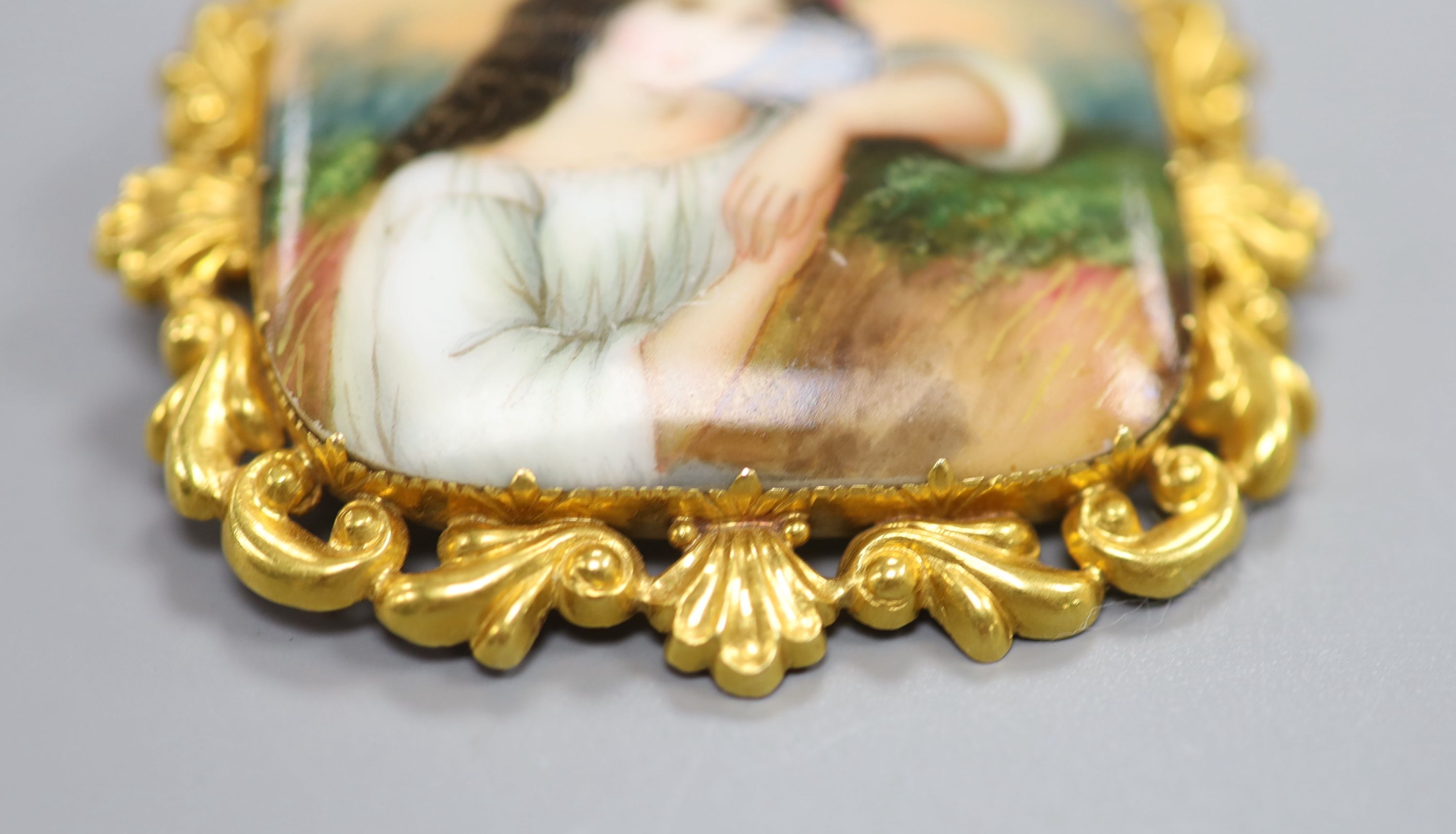 A yellow metal mounted porcelain plaque brooch, painted with a young maiden, 57mm, gross 18.9 grams.